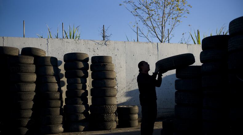 In this Thursday, Nov. 19, 2015, photo, junkyard employee Fabio Flores stacks up used tires at Aadlen Brothers Auto Wrecking, also known as U Pick Parts, in the Sun Valley section of Los Angeles. (AP Photo/Jae C. Hong)