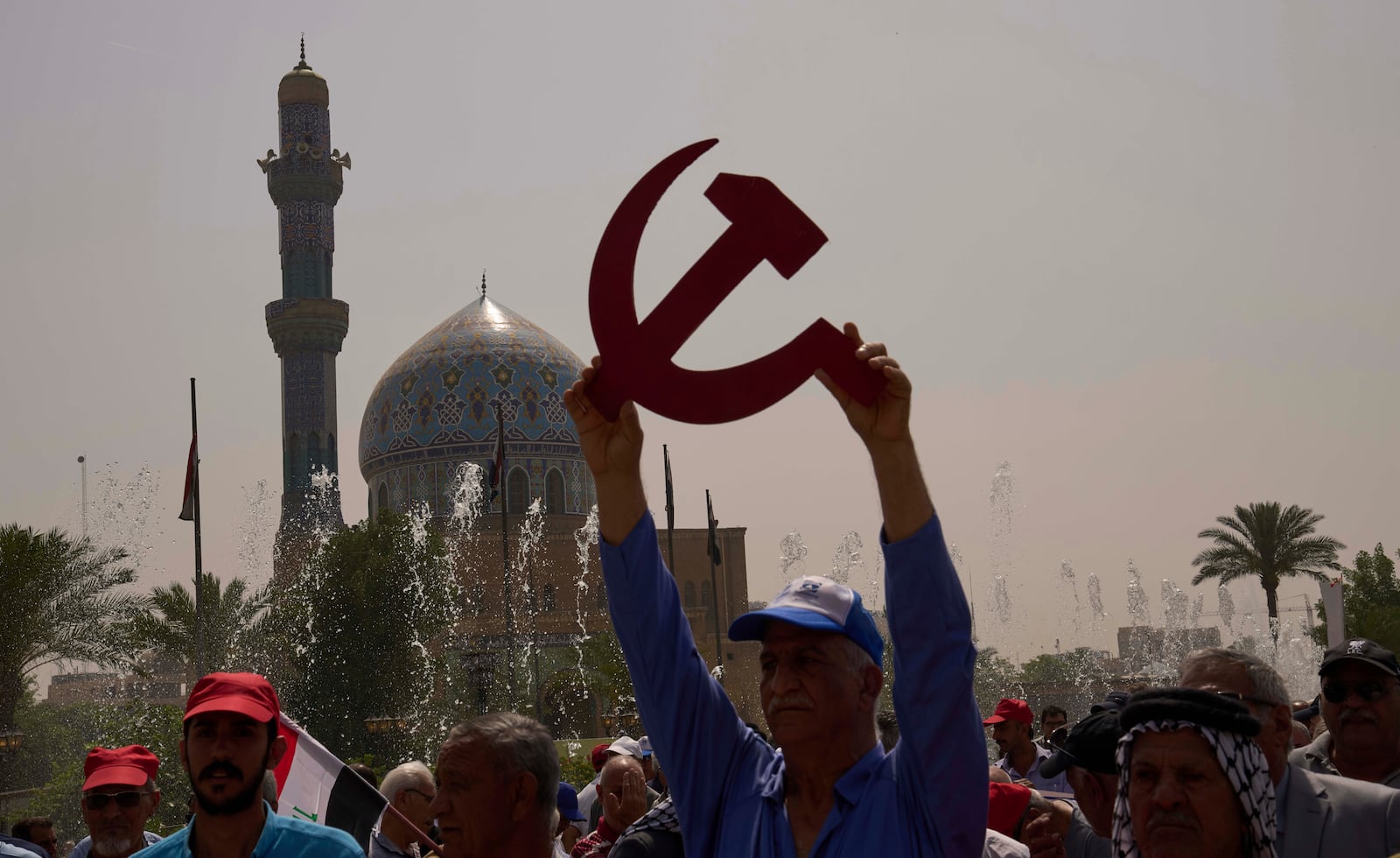 A supporter of the Iraqi Communist Party waves with a symbolic hammer and sickle and the communist flags as they take part in the May Day celebration in Baghdad, Iraq, Thursday, May 1, 2025. (AP Photo/Hadi Mizban)