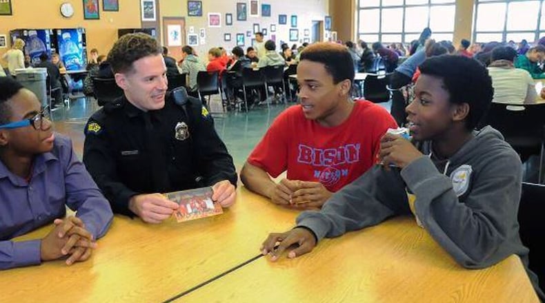 Police officer Zach Hastings and Belmont High School students (from left) Seth Burdette, Kenyon Evans and Billy Veal look at photos of basketball players and discuss scrimmage. JENNIFER BRYANT/CONTRIBUTED