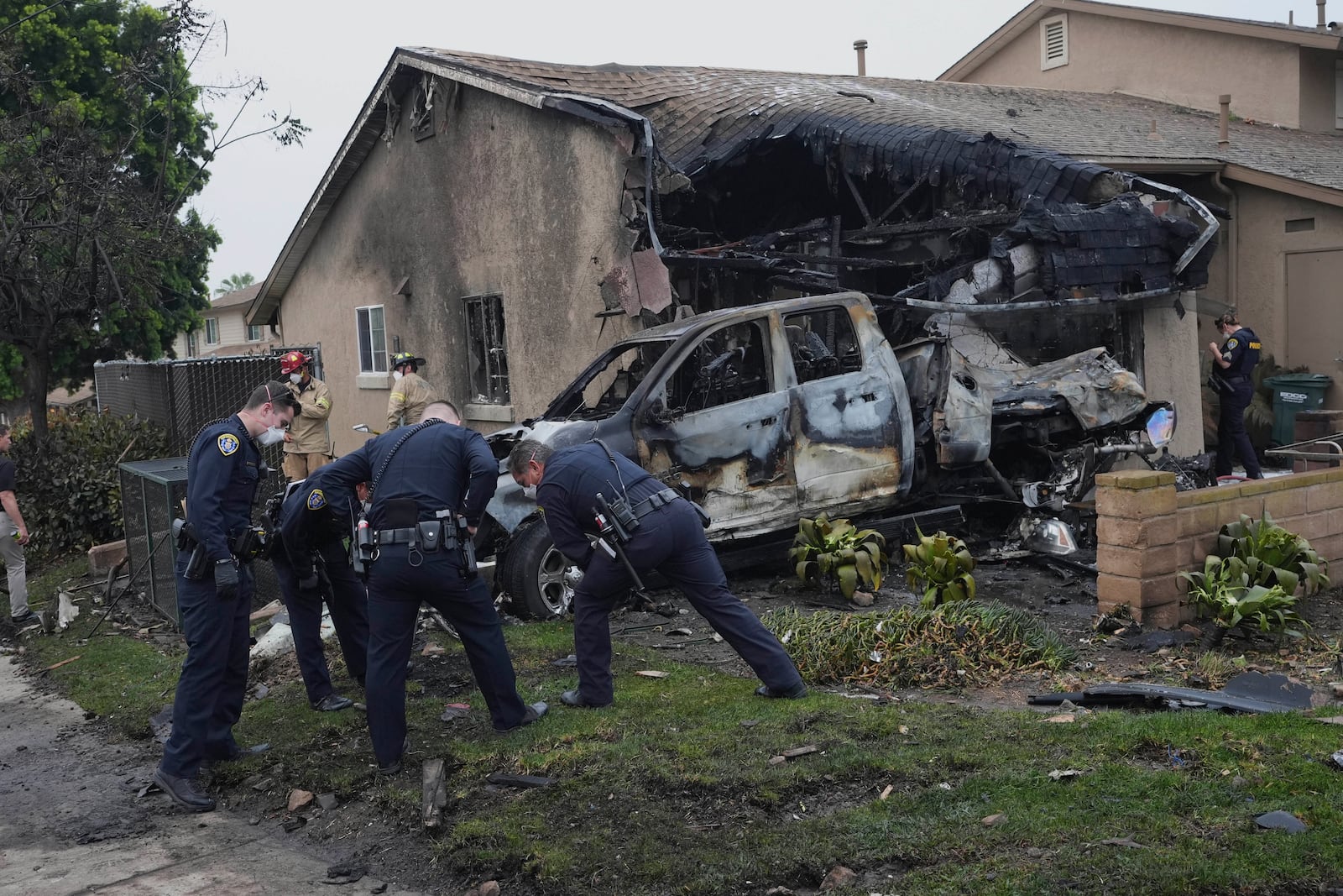 Authorities work the scene where a small plane crashed into a San Diego neighborhood, setting several homes on fire and forcing evacuations along several blocks early Thursday, May 22, 2025. (AP Photo/Gregory Bull)