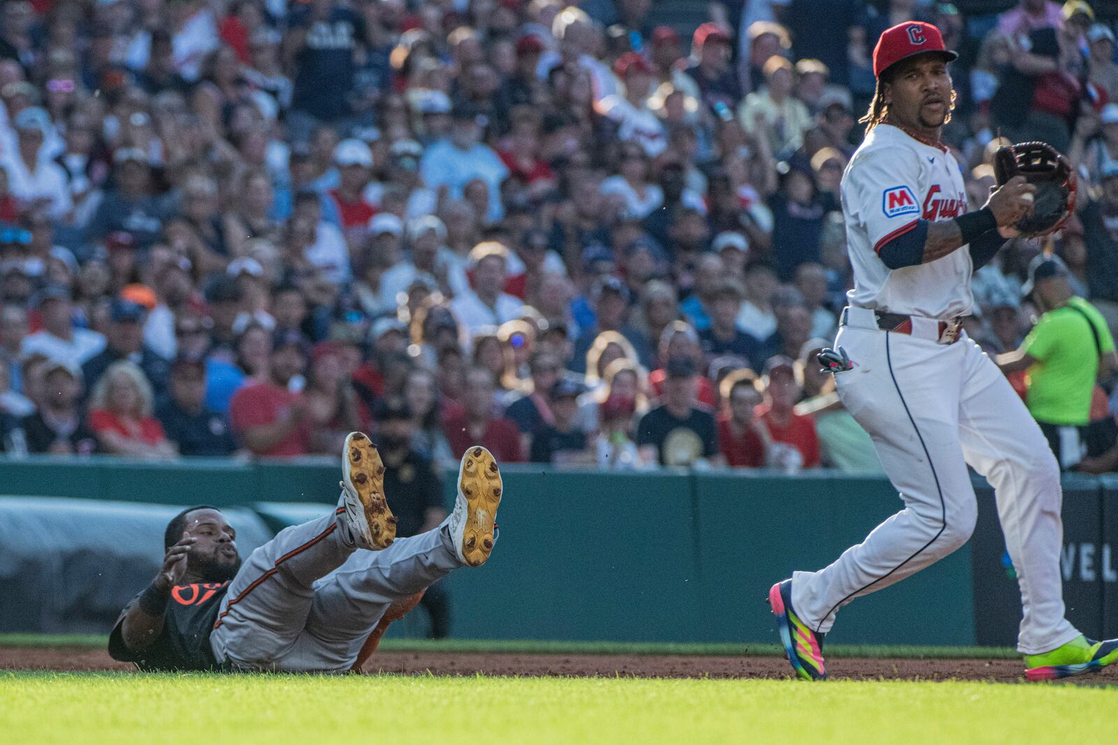 Baltimore Orioles' Cedric Mullins, left, falls down after being tagged out in a rundown by Cleveland Guardians' Jose Ramirez during the third inning of a baseball game, Wednesday, July 23, 2025, in Cleveland. (AP Photo/Phil Long)