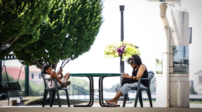Jahleel Boyd and his grandmother, Sharon McGee enjoy some shade at RiverScape in downtown Dayton. McGee said they walked the river walk looking at the ducks and geese until they needed a break from the heat. JIM NOELKER/STAFF