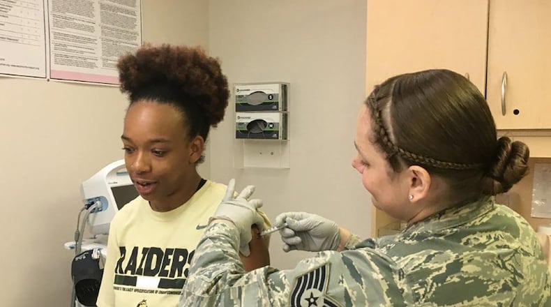 Tech. Sgt. Amanda Buckholdt (right), Wright-Patterson Medical Center Allergy and Immunizations section chief, and Kayle Willis, Allergy and Immunizations administrative technician, demonstrate how the Immunization Clinic administers vaccines to patients on a daily basis. (U.S. Air Force photo/Kimberly Gaither)