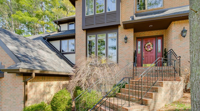 The front entry has brick steps and metal railings leading up to the front door.