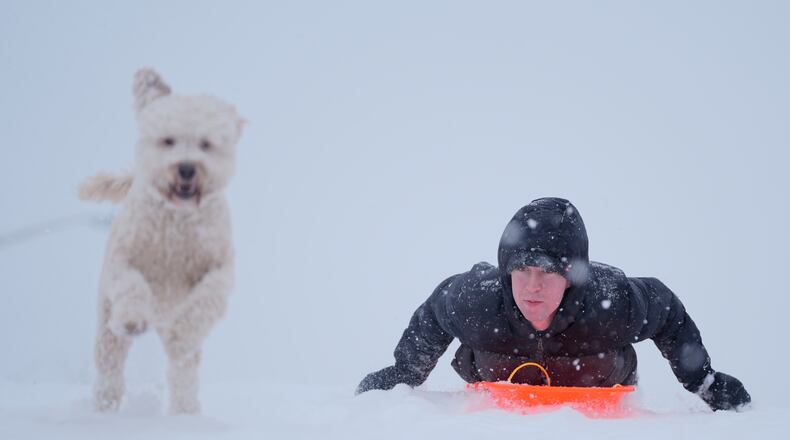 Alex Taylor, 23, and his dog Daisy, make their way down a snowy hill in Charlotte, N.C., Saturday, Jan. 31, 2026. (AP Photo/Erik Verduzco)