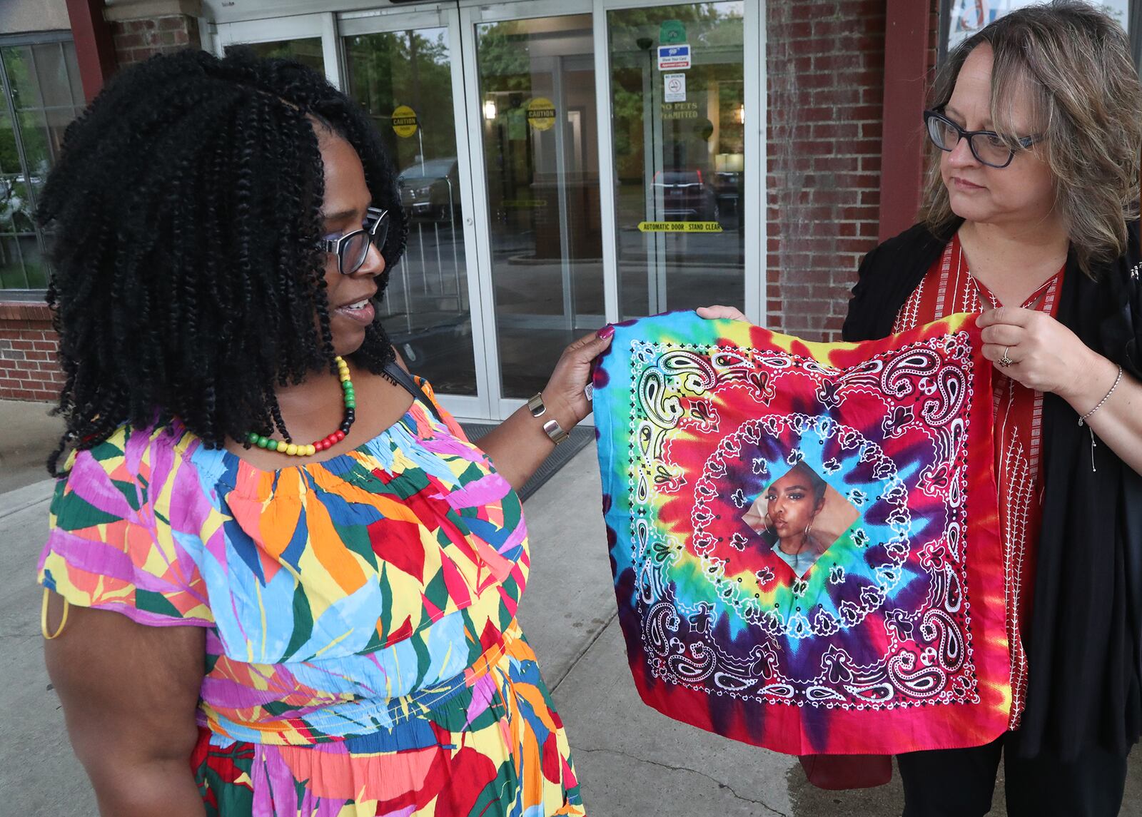Springfield resident Stacy Cameron, left, and her friend, Amy Willmann, hold up a bandana with Stacy's daughter, Shauna Cameron, on it Wednesday, May 18, 2022. Shauna was shot and killed while riding in a car along U.S. 35 in Riverside on May 8, 2022. BILL LACKEY/STAFF