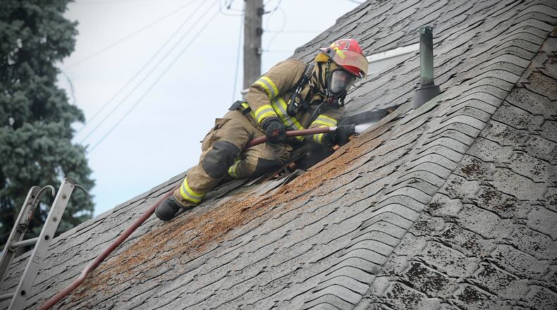 A firefighter is shown on the roof at the scene of a house fire in Champaign County. Two residents and a firefighter were injured in a house fire at 6458 Kiser Lake Road in Rosewood on Saturday, August 13, 2022. The conditions of the residents and the firefighter were unknown Saturday, but all three were transported to area hospitals. MARSHALL GORBY\STAFF
