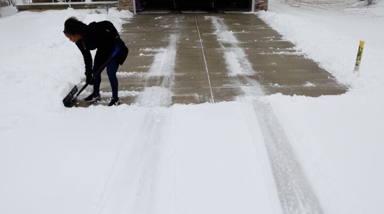 Shaquora Shelley cleans several inches of snow off her Huber Heights driveway Sunday, Feb. 16, 2025. BILL LACKEY/STAFF