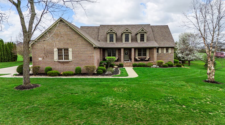 This brick two story features a main level primary suite, covered front porch with stone and brick accents and upper level dormers. The home sits on three acres.