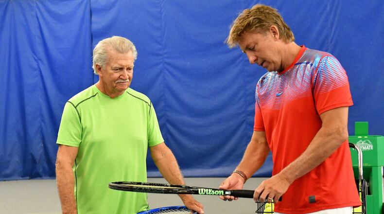 Bud Schroeder (right) talks tennis with a player at his Tipp City tennis center. CONTRIBUTED