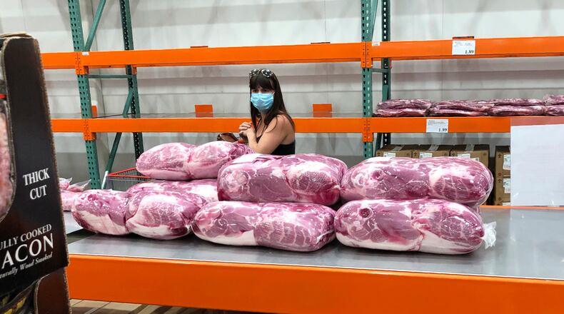 A shopper in a face mask looks over cuts of beef piled up in a cold room for purchase at a Costco warehouse store Tuesday, May 5, 2020, in west Denver.  The U.S. economy rebounded at an even-stronger pace in the July-September quarter than first reported but a resurgence in the coronavirus is expected to slow growth sharply in the current quarter with some analysts even raising the specter of a double-dip recession.  (AP Photo/David Zalubowski)
