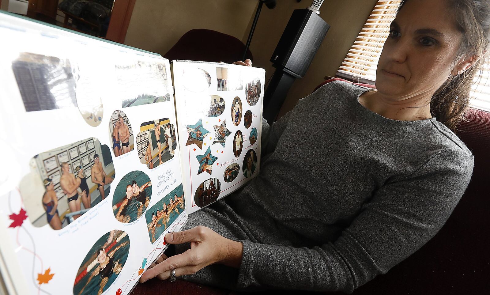 Krissy Randall looks over her scrap book from her shows her Wright State swimming days back in 1992. Bill Lackey/Staff