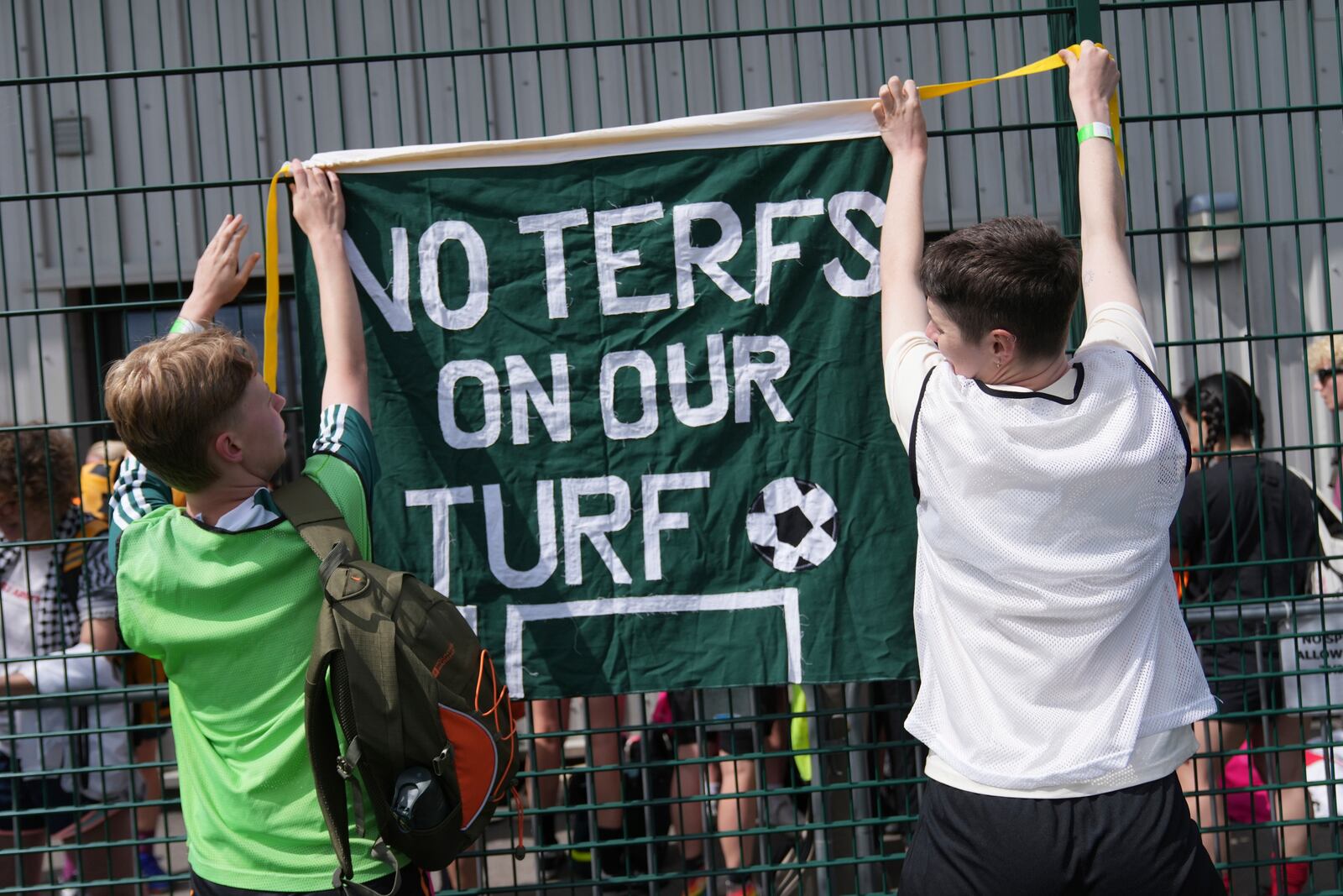 Players put up a banner on the railing surrounding the soccer pitches ahead of an inclusive six a side soccer friendly tournament in London, Sunday, June 1, 2025. (AP Photo/Alastair Grant)