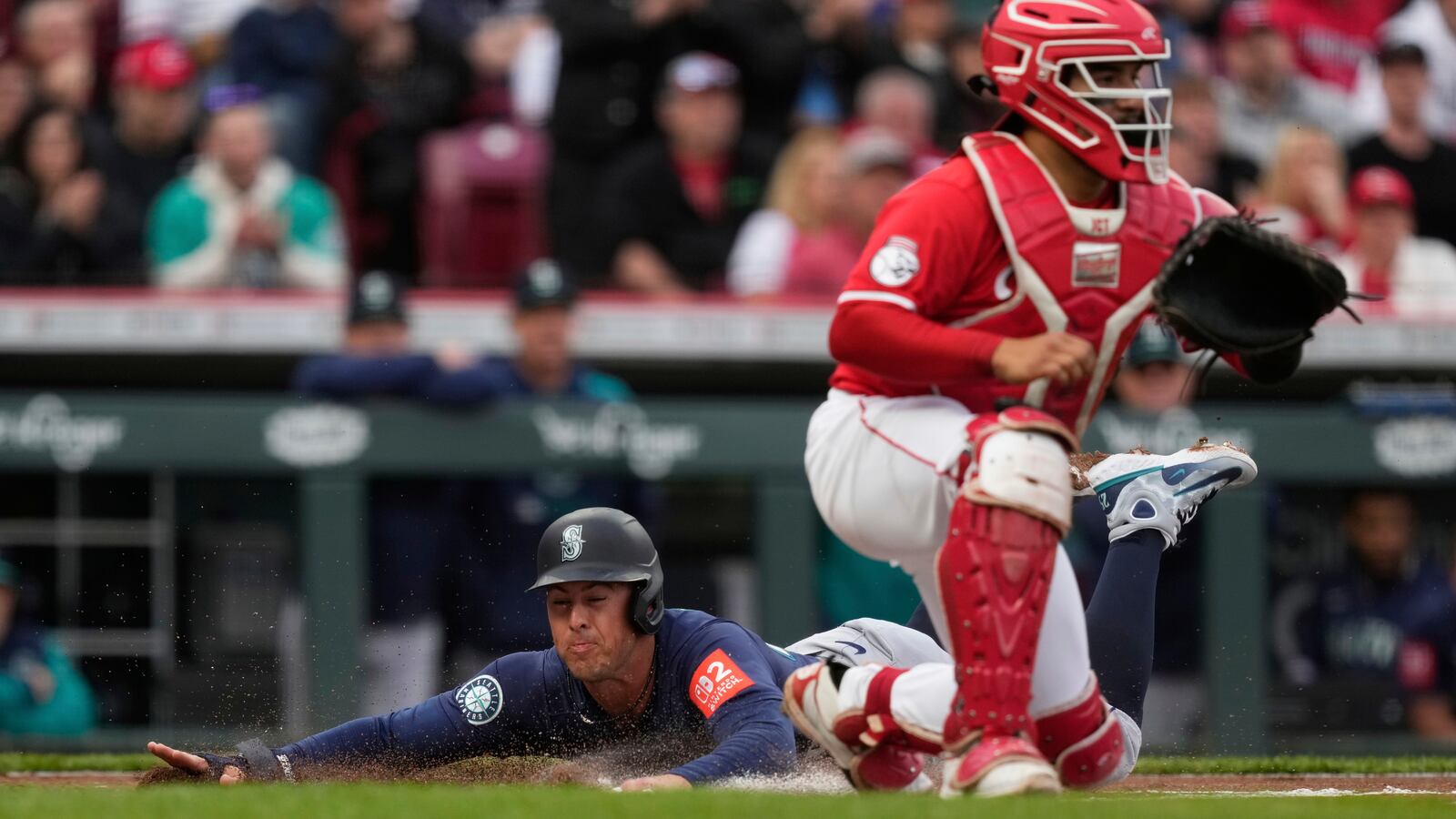 Seattle Mariners' Dylan Moore slides across home plate to score on a single hit by Ben Williamson as Cincinnati Reds catcher Jose Trevino, right, waits for the throw in the second inning of a baseball game, Wednesday, April 16, 2025, in Cincinnati. (AP Photo/Carolyn Kaster)