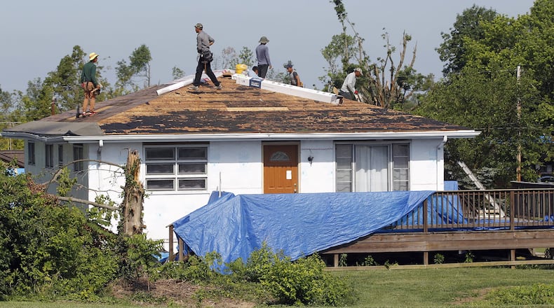 Workers begin the process of re-roofing this house on Graham Drive in Beavercreek that was damaged by the Memorial Day tornado. The City of Beavercreek announced on Thursday that it will end pickup of tree debris from residences on July 28. TY GREENLEES / STAFF