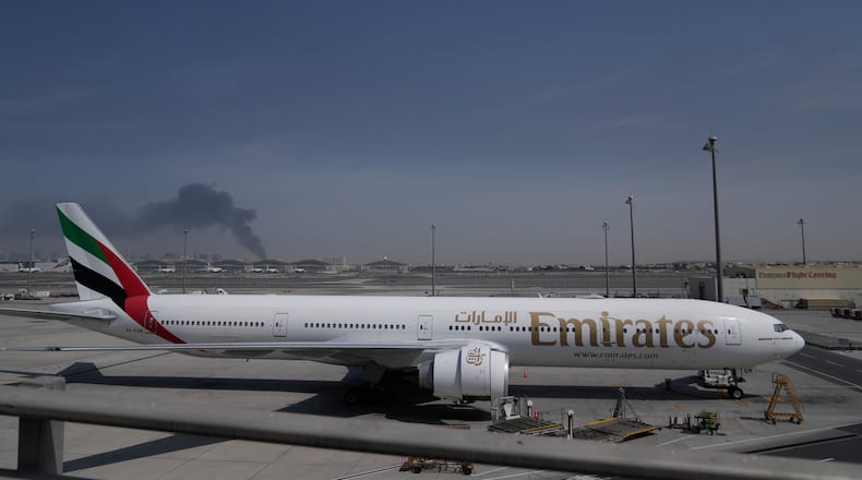 ADDS CAUSE OF BLACK SMOKE IN THE BACKGROUND.- A plume of smoke caused by an Iranian strike is seen in the background an an Emirates plane is parked at the Dubai International Airport after its closure in Dubai, United Arab Emirates, Sunday, March 1, 2026. (AP Photo/Altaf Qadri)