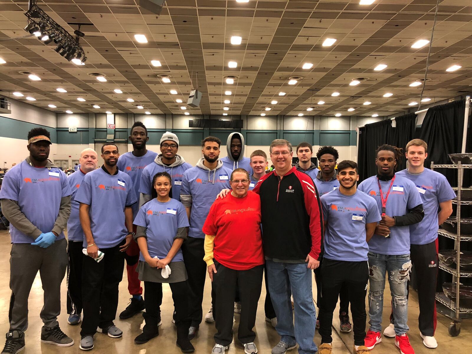 The Sinclair men’s basketball team gathers around Dr, Stephen Levitt, (red shirt ) co-chair of Feast of Giving celebration and Jeff Price (black jacket, red trim) head coach of Sinclair Tartan Pride. CONTRIBUTED PHOTO