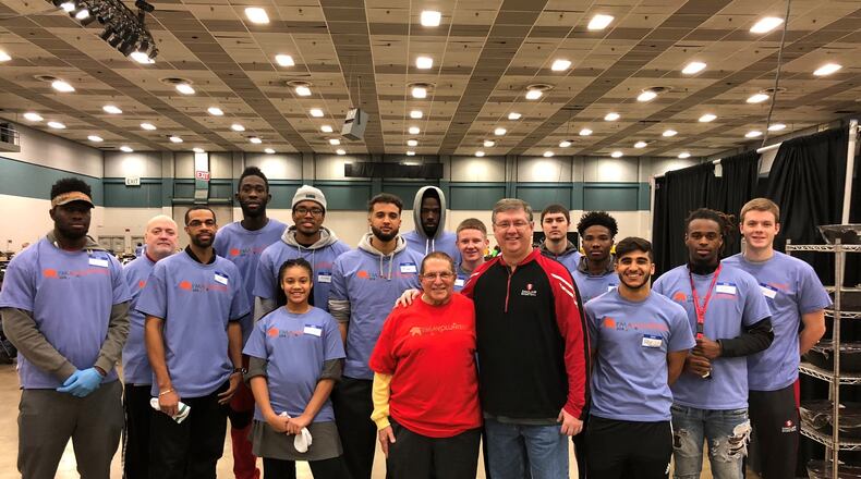 The Sinclair men’s basketball team gathers around Dr, Stephen Levitt, (red shirt ) co-chair of Feast of Giving celebration and Jeff Price (black jacket, red trim) head coach of Sinclair Tartan Pride. CONTRIBUTED PHOTO