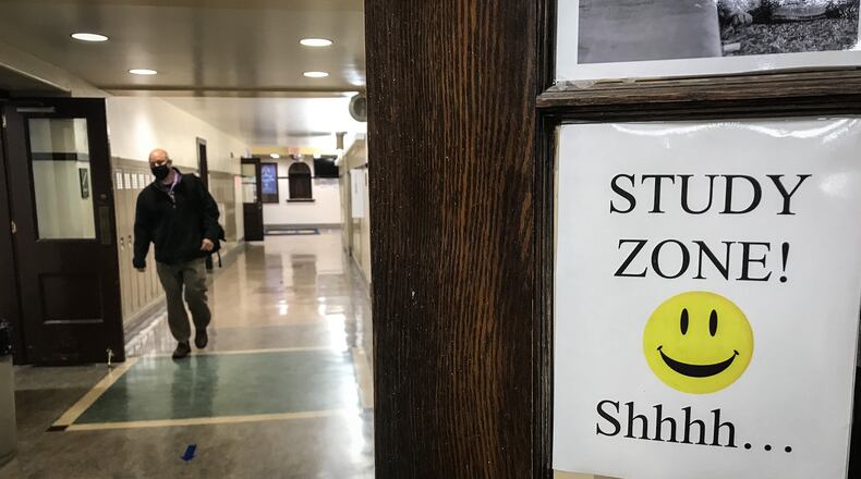 A teachers walks down an empty hallway at Oakwood Jr. High School. The school has been using the same plan all year where students attend half-days, five days a week.