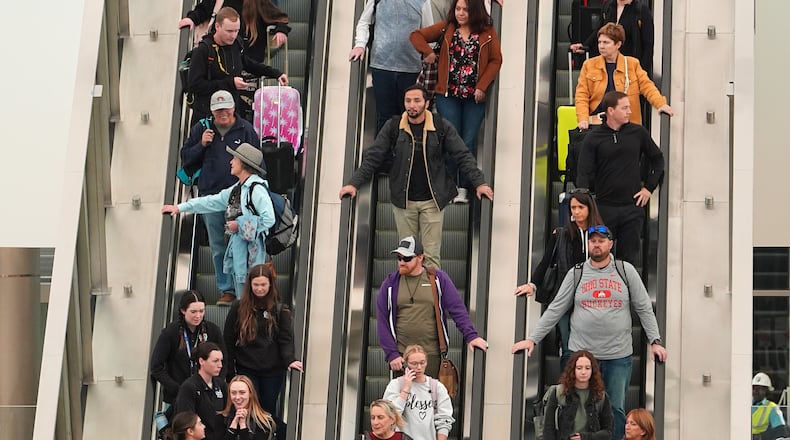 Travellers head down an escalator after clearing through a security checkpoint in Denver International Airport Friday, Nov. 7, 2025, in Denver. (AP Photo/David Zalubowski)