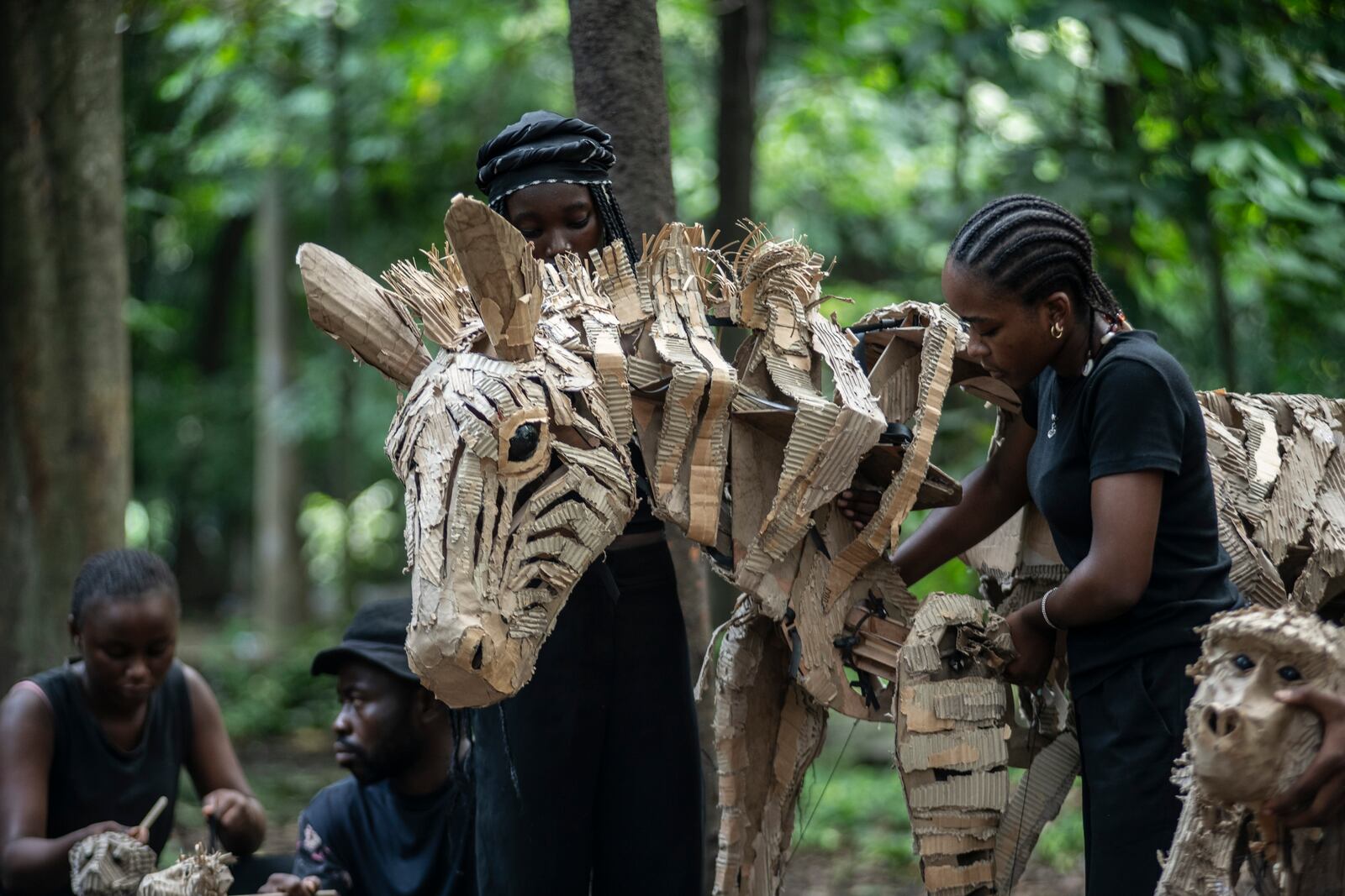 Puppeteers move cardboard animals through DRC's capital Kinshasa's botanical gardens Thursday, April 10, 2025, the first steps of "The Herds", a moving theatre performance that will travel from the Democratic Republic of the Congo to the Arctic Circle in a bid to bring attention to the climate crisis. (AP Photo/Samy Ntumba Shambuyi)