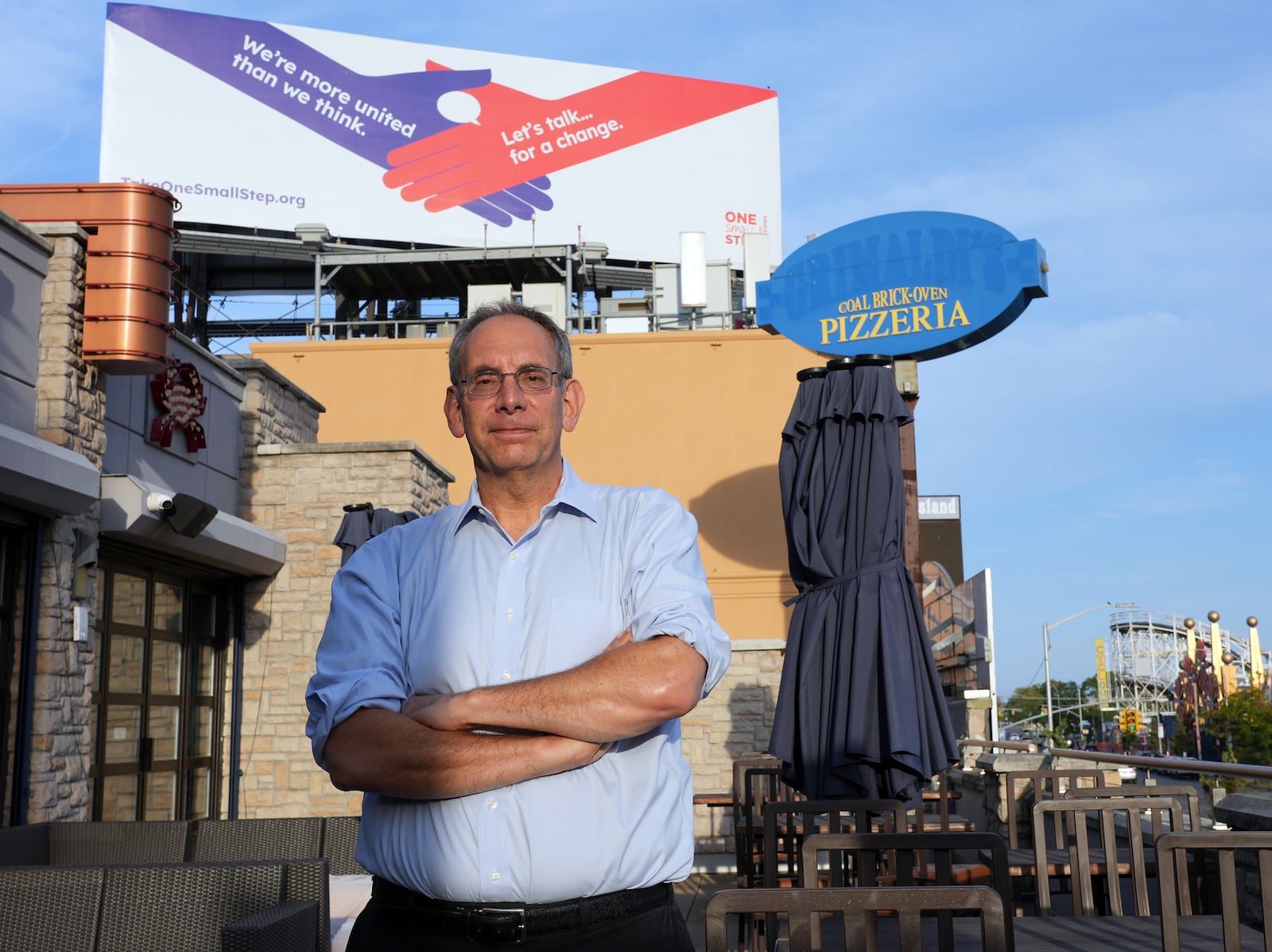 
                        Dave Isay, the founder of StoryCorps, in front of a billboard in Brooklyn advertising the One Small Step initiative, Sept. 17, 2024. One Small Step, an initiative that facilitates conversations between people with opposing views, is trying to tackle political polarization. (Michelle V. Agins/The New York Times)
                      
