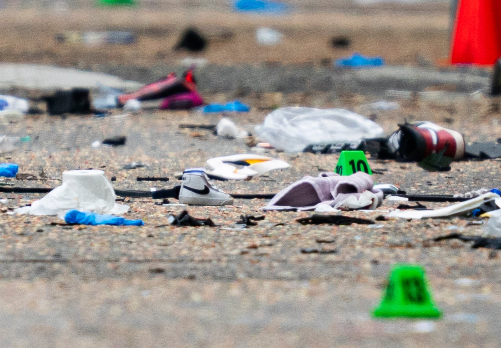 A small shoe lies among the debris and evidence markers on the street while police investigate after a vehicle drove into a crowd Saturday killing multiple people at a street festival, in Vancouver, British Columbia, Sunday, April 27, 2025. (Rich Lam/The Canadian Press via AP)