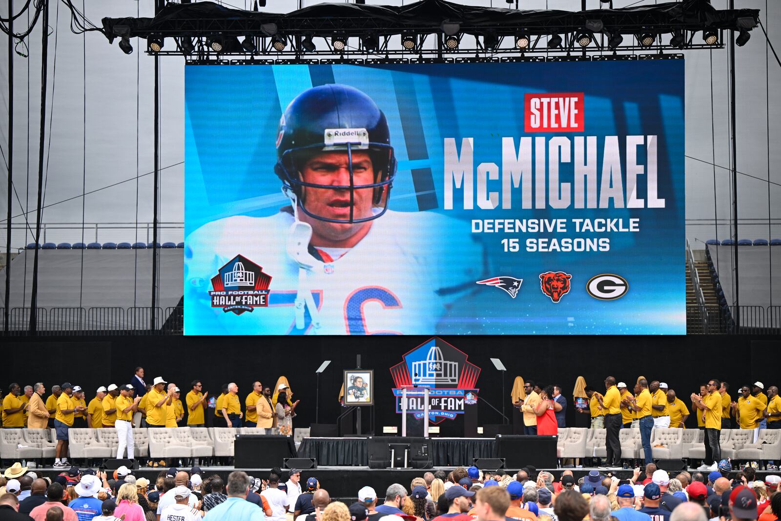 FILE - A video board displays an image of former NFL player Steve McMichael during his induction into the Pro Football Hall of Fame, in Canton, Ohio, Saturday, Aug. 3, 2024. (AP Photo/David Richard,File)