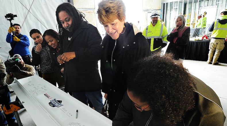 Members of the Dayton school board and staff sign the last beam to go up on the new press box at Welcome Stadium on Thursday, April 6, 2023. From right are Chrisondra Goodwine, Elizabeth Lolli, Will Smith, Hiwot Abraha and Victoria Jones. MARSHALL GORBY\STAFF