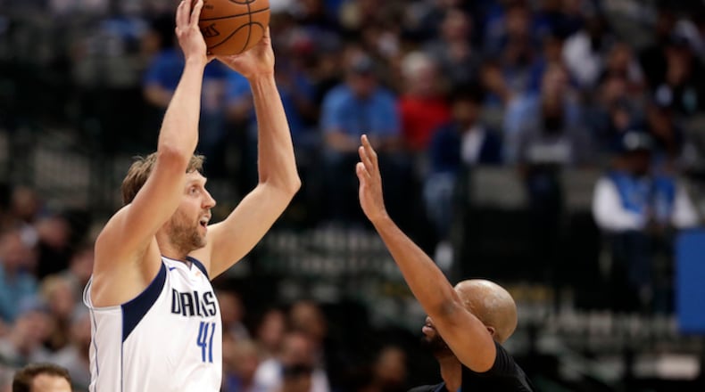 Dallas Mavericks' Dirk Nowitzki (41) of Germany passes the ball as Minnesota Timberwolves' Taj Gibson defends during an NBA basketball game in Dallas, Friday, March 30, 2018. (AP Photo/Tony Gutierrez)