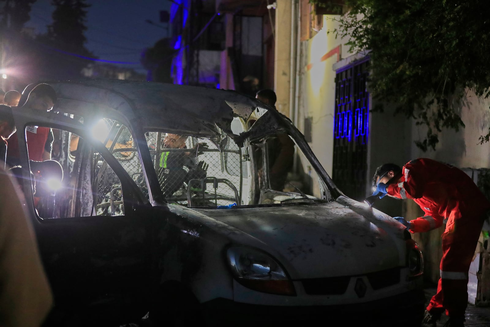 Rescue workers inspect a damaged car after an Israeli strike, in the southern port city of Sidon, Lebanon, early Wednesday, May 7, 2025. (AP Photo/Mohammed Zaatari)