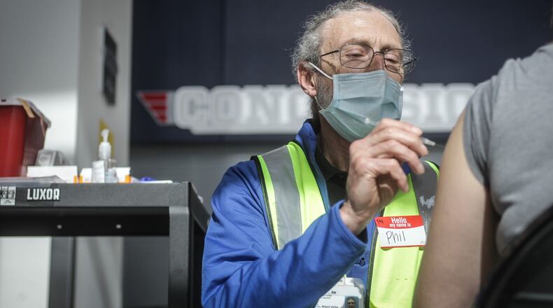 Premier Health R.N. Phil Frederick administers a COVID-19 vaccine at the University of Dayton Arena.