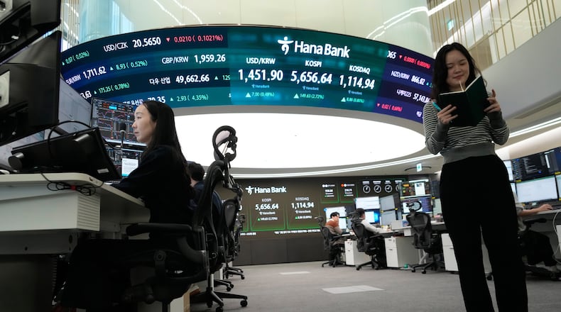 Currency traders work near a screen showing the Korea Composite Stock Price Index (KOSPI), top center, and the foreign exchange rate between U.S. dollar and South Korean won, top center left, at the foreign exchange dealing room of the Hana Bank headquarters in Seoul, South Korea, Thursday, Feb. 19, 2026. (AP Photo/Ahn Young-joon)