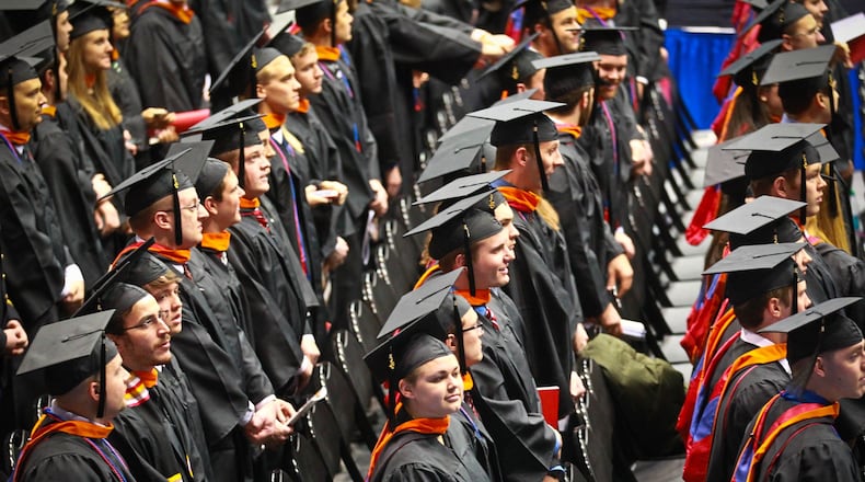 University of Dayton graduates stand at their seats during the processional at the 164th commencement ceremony held in the UD Arena saturday.JIM WITMER / STAFF