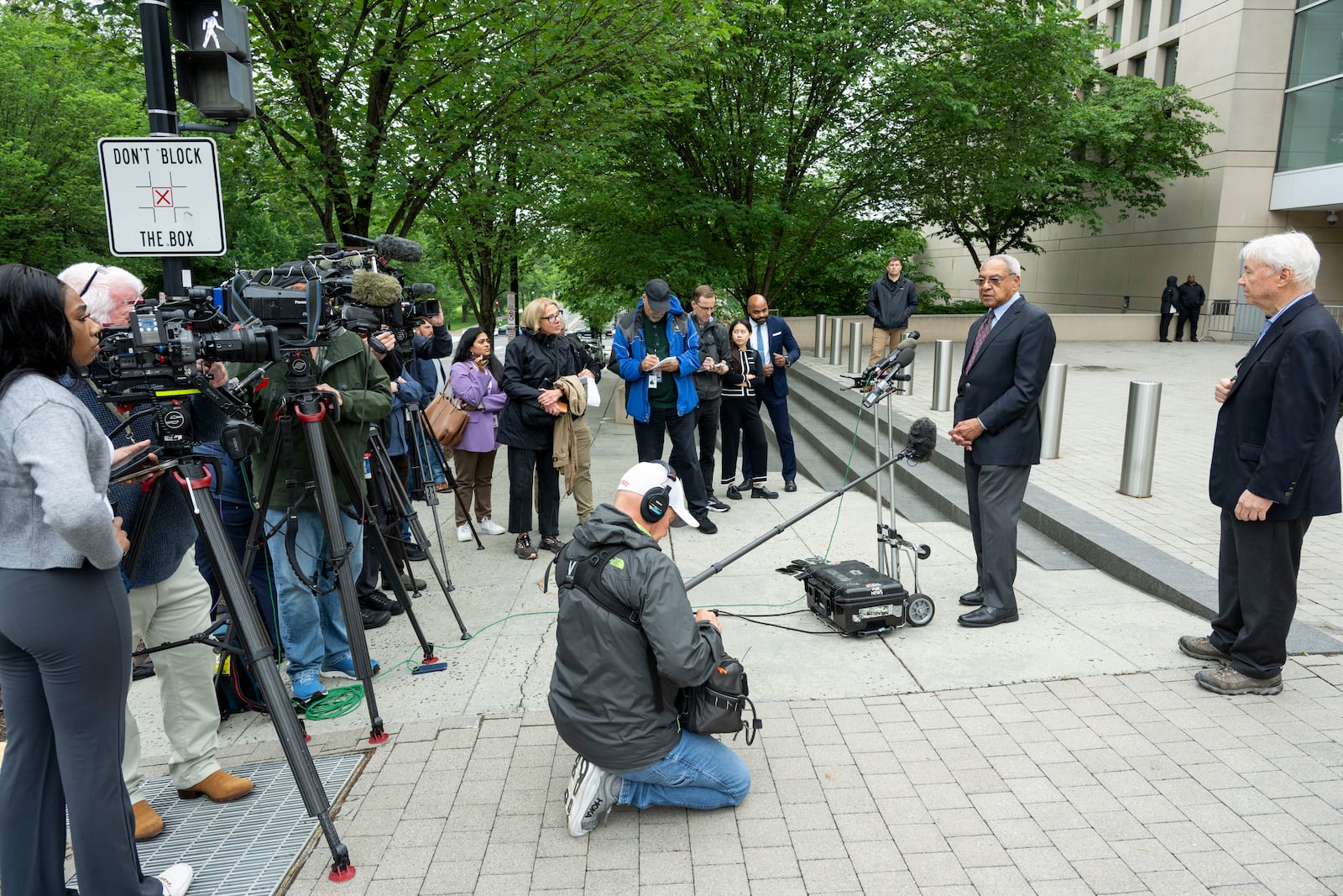 U.S. Institute of Peace (USIP) acting President George Moose, second from right, and USIP acting Counsel George Foote, right, to talk to the press outside the Institute, Wednesday, May 21, 2025 in Washington. (AP Photo/Kevin Wolf)
