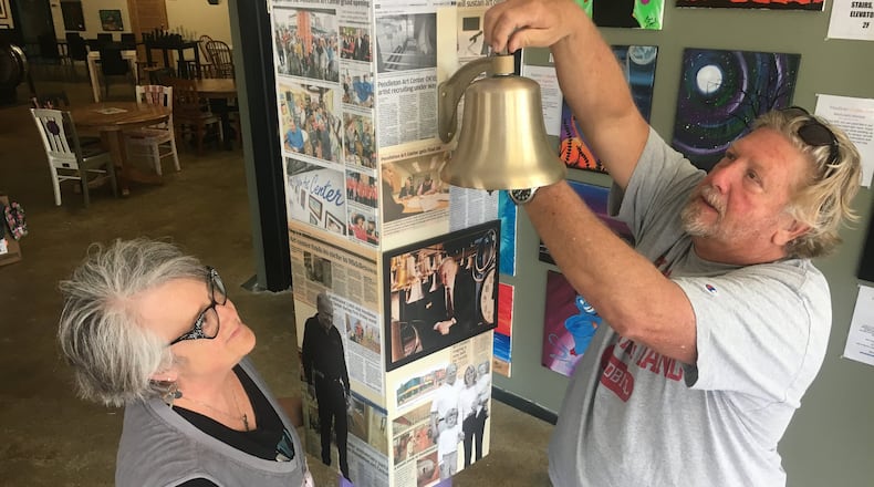 Artists Glenda Miles and Rex Combs install the Verdin Bell Wednesday morning at the Pendleton Art Center in downtown Middletown. First-time visitors to the PAC will be encouraged to ring the bell in honor of the late Jim Verdin, the driving force behind the center. The bell will be dedicated at 5 p.m. Friday. RICK McCRABB/STAFF