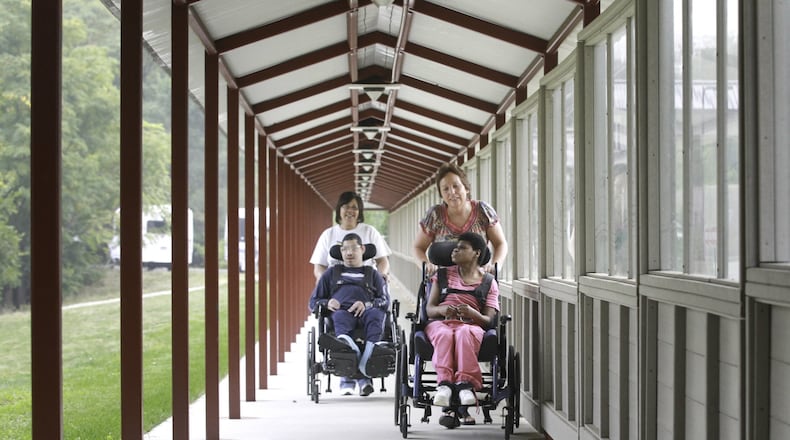 Stillwater Center employees Debbie Bowser, right, and T.C. Rabb shuttle residents of the residential center for those with severe and profound disabilities down new walkway. The covered walkway allows the residents to get from the center to Northview School for programs. Before, many of the residents were traveling about 11 miles by bus for services at another school. CHRIS STEWART / STAFF