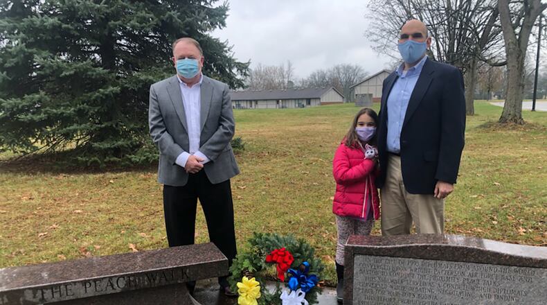 Retired Air Force Lt. Col. John McCance (left) and Matt Joseph, Dayton city commissioner, take part in a private wreath-laying ceremony Nov. 21 at the Peace Walk bench and plaque on Wright-Patterson Air Force Base to commemorate the 25th anniversary of the Dayton Peace Accords, which ended the brutal Bosnian War. The two serve as co-chairs of the anniversary events committee. Also pictured is Joseph’s daughter, Sara. In 1995, the peace talks unfolded over 20 days at Hope Hotel (now the Hope Hotel and Richard C. Holbrooke Conference Center.) The accords were signed in Paris on Dec. 14 that year, which ended civil war and genocide in Bosnia-Herzegovina, a small southeast European country once part of Yugoslavia. COURTESY PHOTO/DONNA SCHLAGHECK