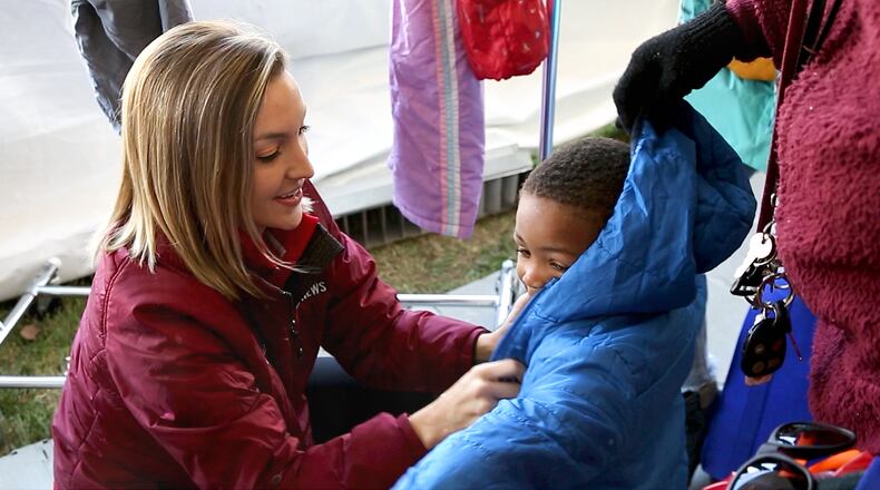 WDTN-TV anchor Brooke Moore helps a young boy bundle up in a winter jacket. Coats for men, women and children were collected for the annual Coats for Kids drive. CONTRIBUTED