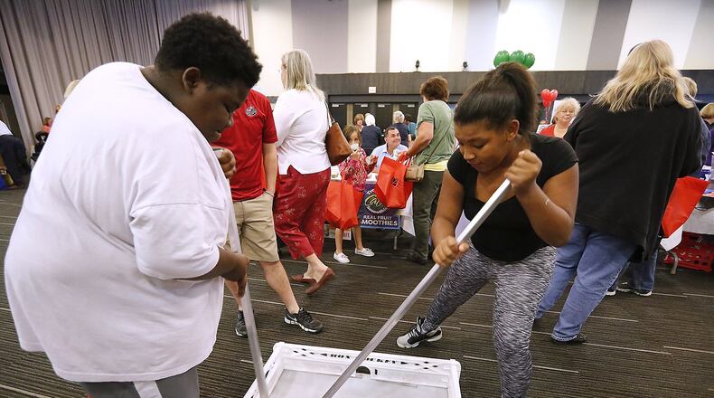 Tykel Belle and his sister, Keyila, play a game of hockey at the National Trail Parks and Recreations Chiller booth during the Health Expo at the Hollenbeck Bayley Arts and Conference Center Tuesday. Bill Lackey/Staff