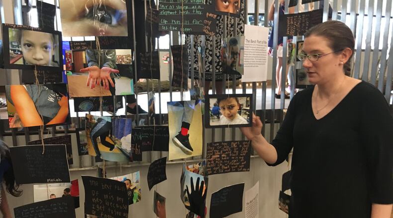 Miracle Makers after-school program education director Ellen Mays looks at part of a photo exhibit by Miracle Makers students at Dayton Metro Library downtown. This exhibit asks students to photograph and write about their favorite part of themselves. Other parts of the exhibit focused on improving their community. STAFF/JOSH SWEIGART