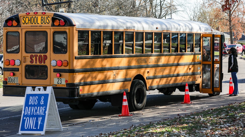 Staff members wait for children to be dismissed from Oakview Elementary School in a bus pickup lane on Monday, Nov. 17, in Kettering. BRYANT BILLING/STAFF