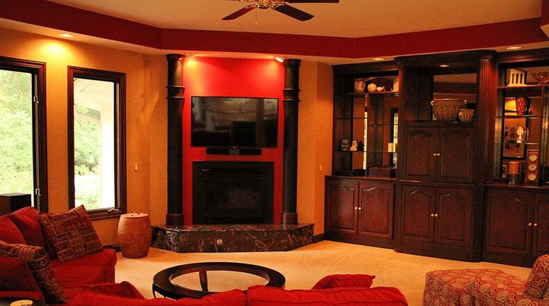 The open hearth room offers a gas fireplace and multiple built-ins under a tray ceiling that follows the quasi-elliptical shape of the room.