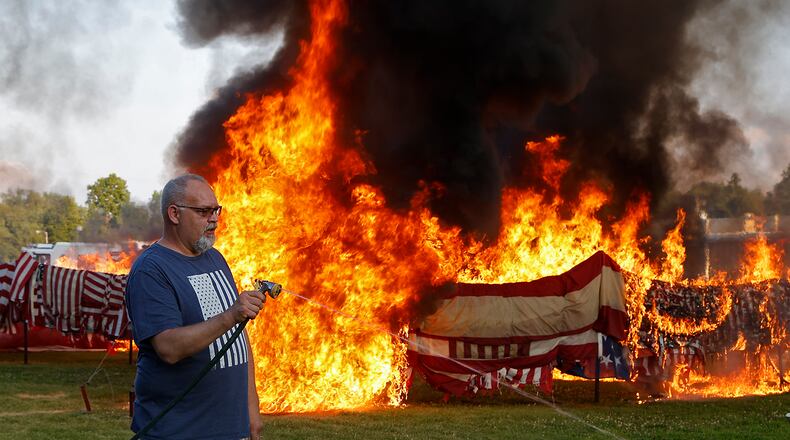Tony Rieker extinguishes the torches after helping light thousands of American flags during the annual flag retirement ceremony at American Legion Post 286 in New Carlisle Friday, June 14, 2024. The American Legiion receives thousands of faded and worn out flags from all over the country to officially retire. This year they retired between 8,000 an 10,000 flags. BILL LACKEY/STAFF
