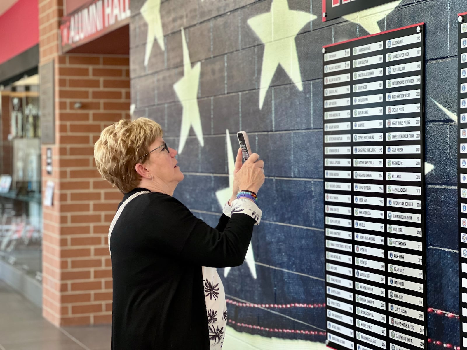 Terri Milligan takes a photo of her son Tyler's name on the Wayne High School Wall of Honor. Tyler graduated from Wayne in 2008 and served in the Navy for 11 years. AIMEE HANCOCK/STAFF