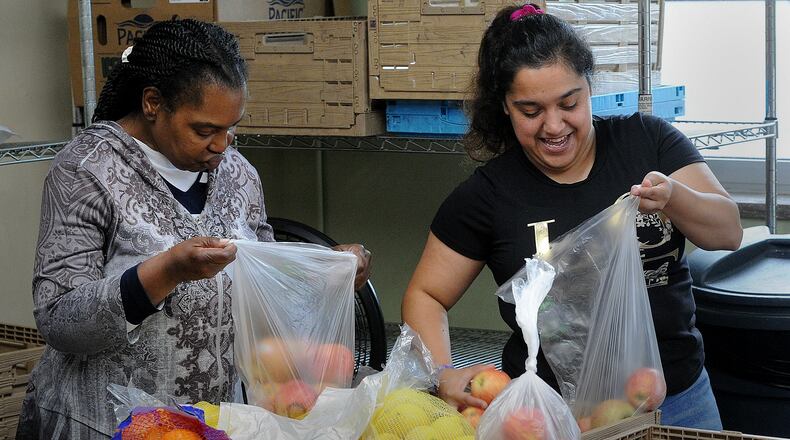 Catholic Social Services volunteers, Lisa Adegvile, left and Anaise Sahnais, bags fruits and vegetables for people receiving groceries, Thursday, July 6, 2023. MARSHALL GORBY\STAFF