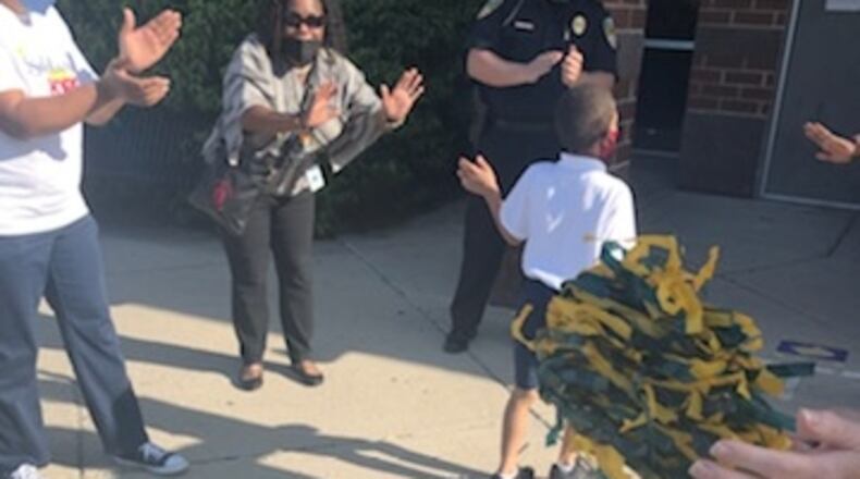 Dormetria Thompson (center) and other community members cheer as students arrive for class at Fairview Elementary School.