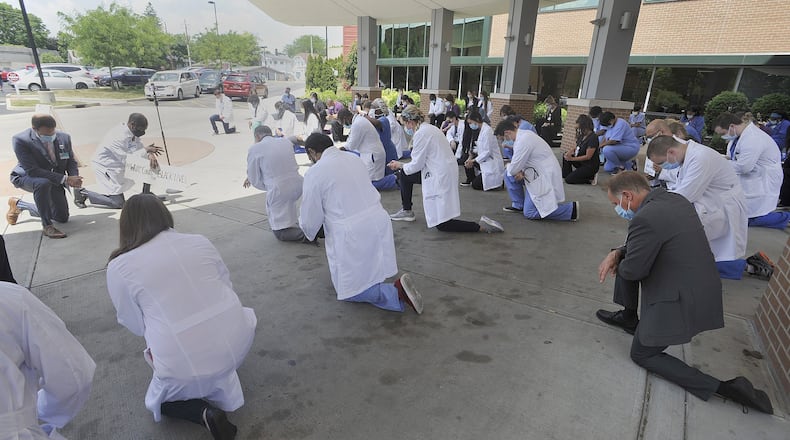 Grandview Medical Center staff kneel in their white coats Friday as part of White Coats for Black Lives. They joined healthcare professionals across the county in a moment of silent reflection and commitment to improve the health and safety of peopleof color. MARSHALL GORBYSTAFF