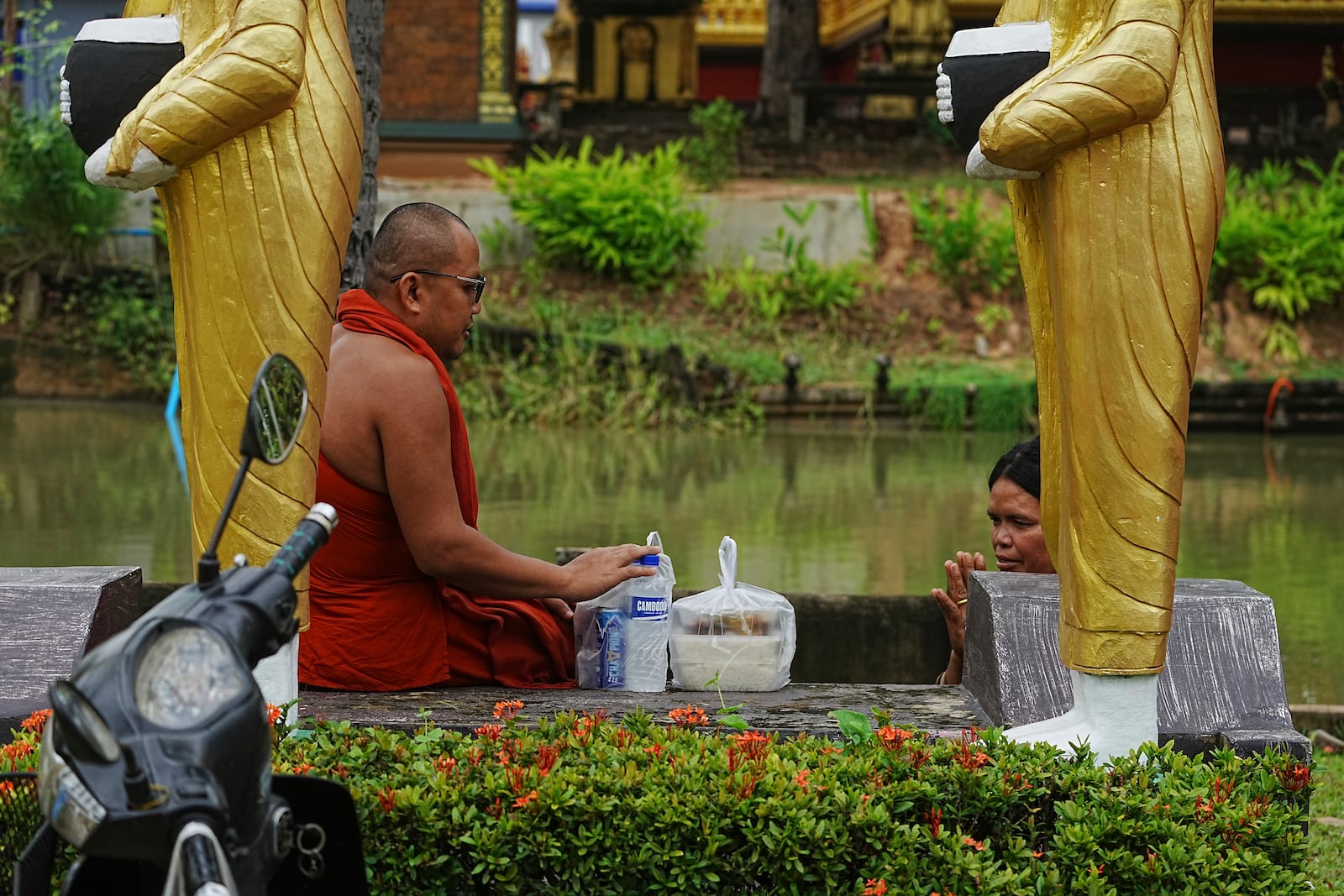 A Cambodian Buddhist monk, left, receives food from a devotee, right, in Wat Prasat Samrong Pagoda in Oddar Meanchey province, Cambodia, Saturday, July 26, 2025, as border fighting between Thailand and Cambodia entered its third day. (AP Photo/Heng Sinith)
