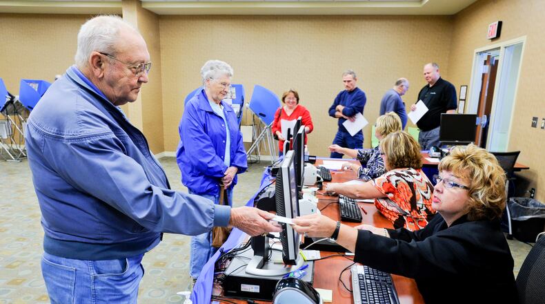 Donna Defazio hands a voting card to Marion Mink during the first day of early voting in 2012 in Butler County. Defazio, who worked for the Butler County Board of Elections for 10 years, died Monday. She was 63. NICK GRAHAM/2012